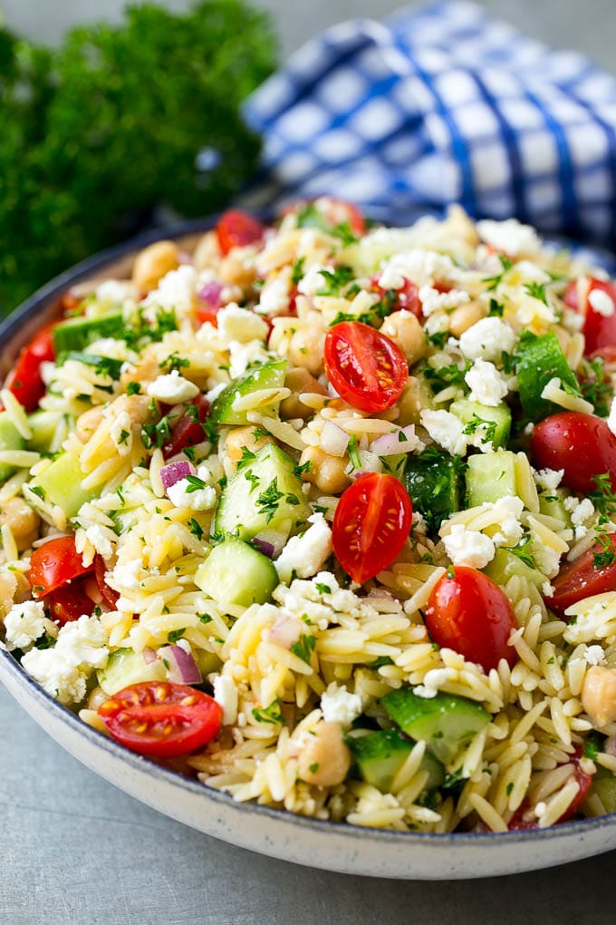 Orzo Salad Recipe | Orzo Pasta Salad | Greek Orzo Salad | Mediterranean Orzo Salad #pastasalad #orzo #greekfood #salad #jonep Orzo salad in a serving bowl with tomatoes, cucumbers and chickpeas.