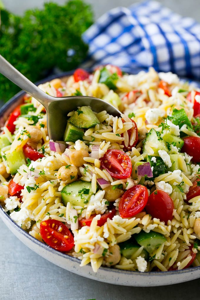 Orzo Salad Recipe | Orzo Pasta Salad | Greek Orzo Salad | Mediterranean Orzo Salad #pastasalad #orzo #greekfood #salad #jonep Orzo pasta salad with a serving spoon in the bowl.