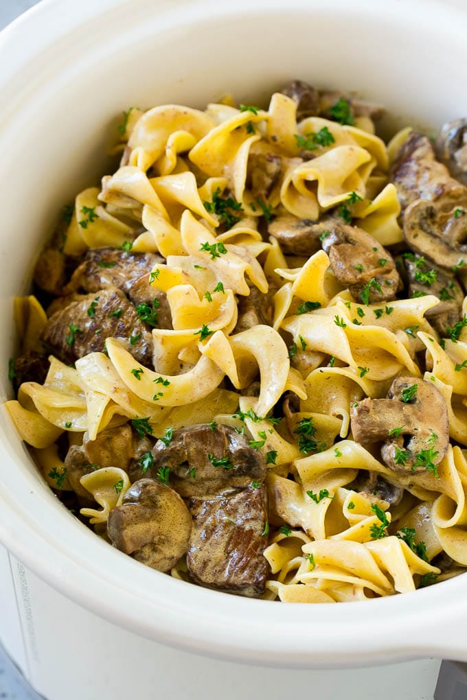 Slow Cooker Beef Stroganoff Recipe | Crock Pot Beef Stroganoff | Beef Recipe #slowcooker #crockpot #beef #mushrooms #pasta #dinner #jonep Slow cooker beef stroganoff with chunks of beef, mushrooms and egg noodles topped with parsley.