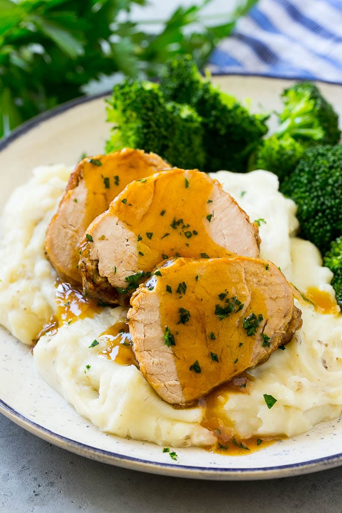 Slow Cooker Pork Tenderloin Recipe | Crock Pot Pork Tenderloin | Easy Pork Tenderloin #slowcooker #crockpot #pork #dinner #jonep Sliced slow cooker pork tenderloin served over mashed potatoes with broccoli.