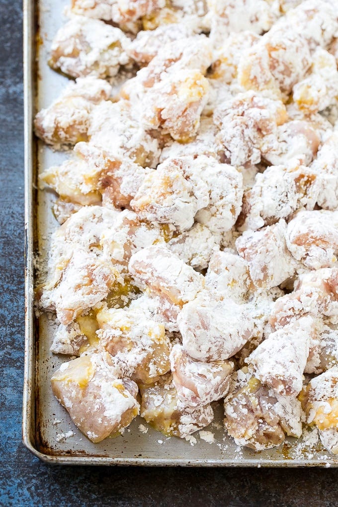 Sweet and Sour Chicken Recipe | Chinese Food Copycat Recipe | Chicken with Pineapple #chicken #chinesefood #pineapple #stirfry #takeout #dinner #jonep Chicken pieces coated in egg and flour on a baking sheet.