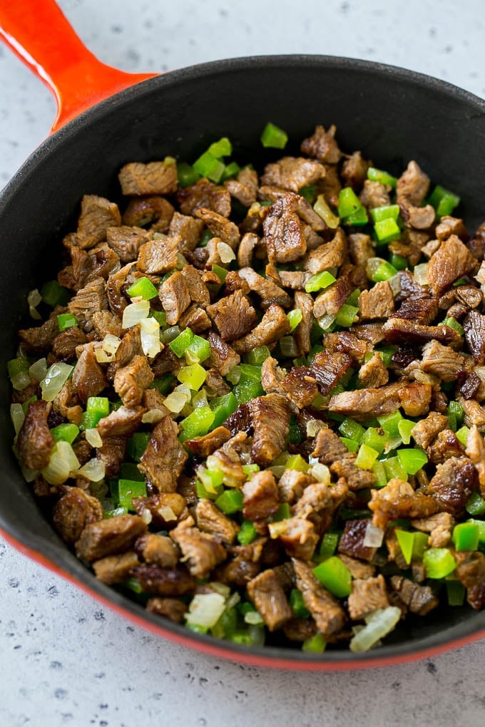Philly Cheesesteak Dip Recipe | Cheesy Dip | Baked Cheese Dip #steak #dip #appetizer #cheese #jonep Seared rib eye steak, peppers and onions in a pan.