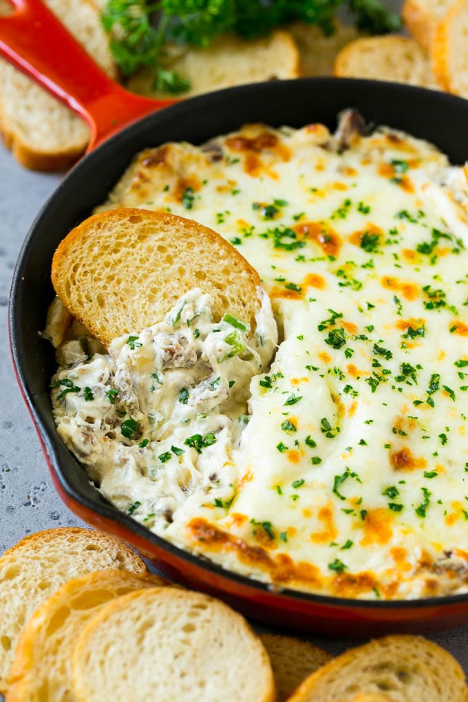 Philly Cheesesteak Dip Recipe | Cheesy Dip | Baked Cheese Dip #steak #dip #appetizer #cheese #jonep Philly cheesesteak dip with a baguette piece scooping some dip out.