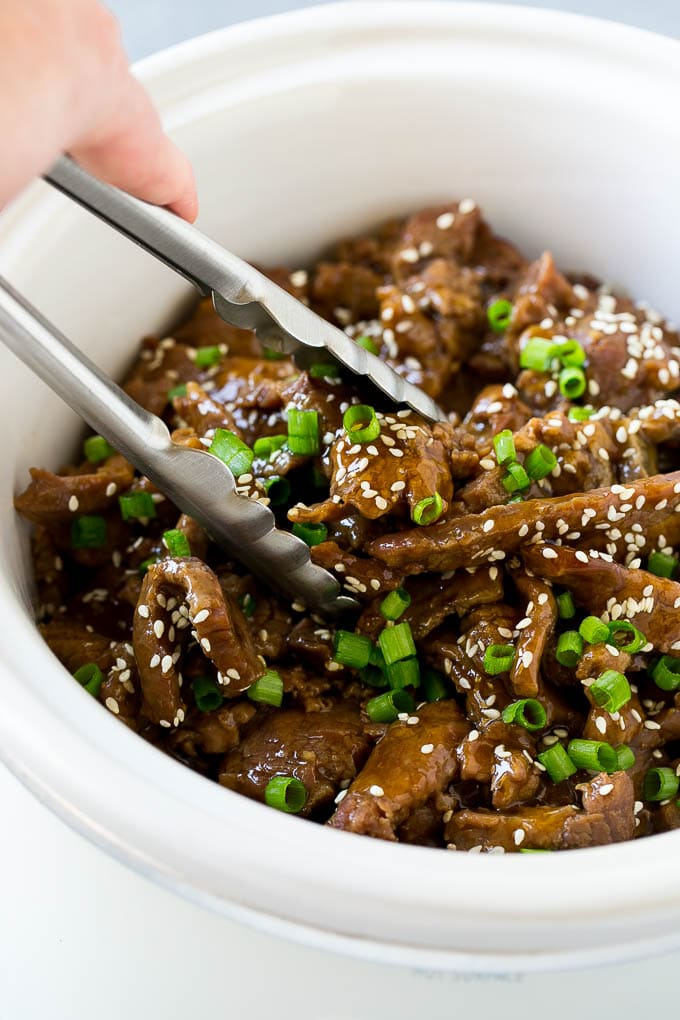 Slow Cooker Korean Beef Recipe | Korean Beef | Flank Steak Recipe #dinner #beef #slowcooker #crockpot #asian #jonep A crock pot of Korean beef with serving tongs in it.