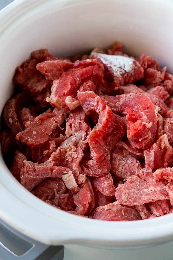 Slow Cooker Korean Beef Recipe | Korean Beef | Flank Steak Recipe #dinner #beef #slowcooker #crockpot #asian #jonep Flank steak strips tossed in cornstarch inside a slow cooker.
