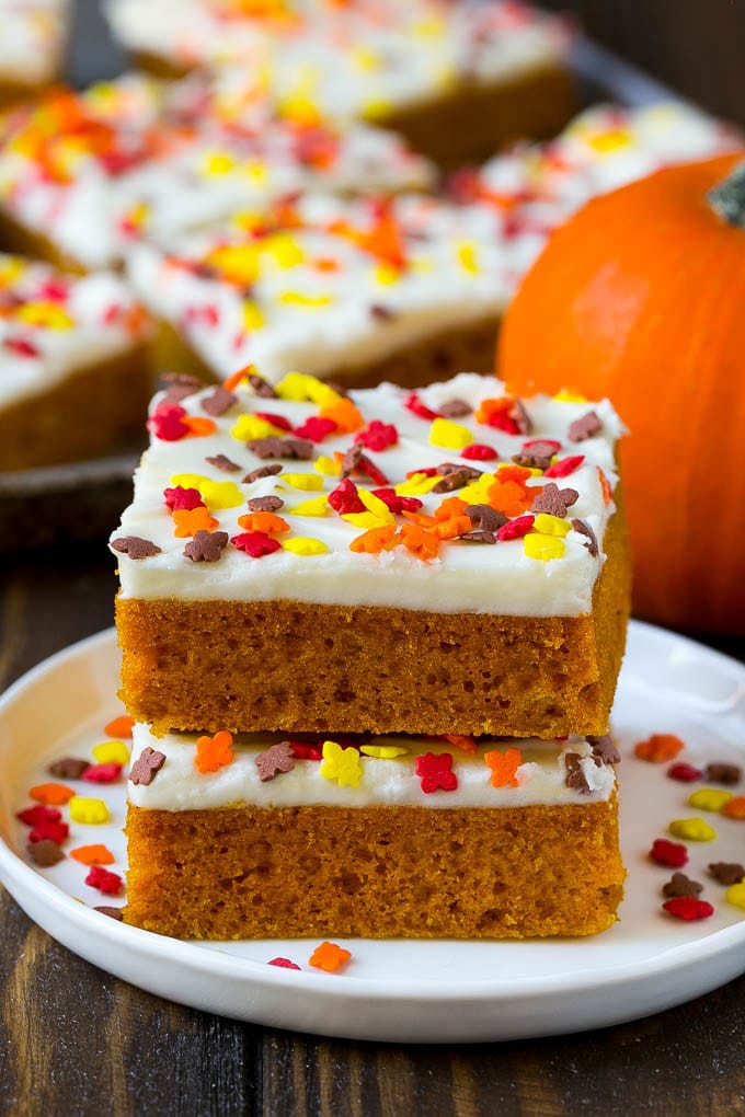 Pumpkin Bars Recipe | Pumpkin Cake | Pumpkin Dessert #pumpkin #fall #dessert #jonep #thanksgiving A stack of pumpkin bars topped with frosting and sprinkles.
