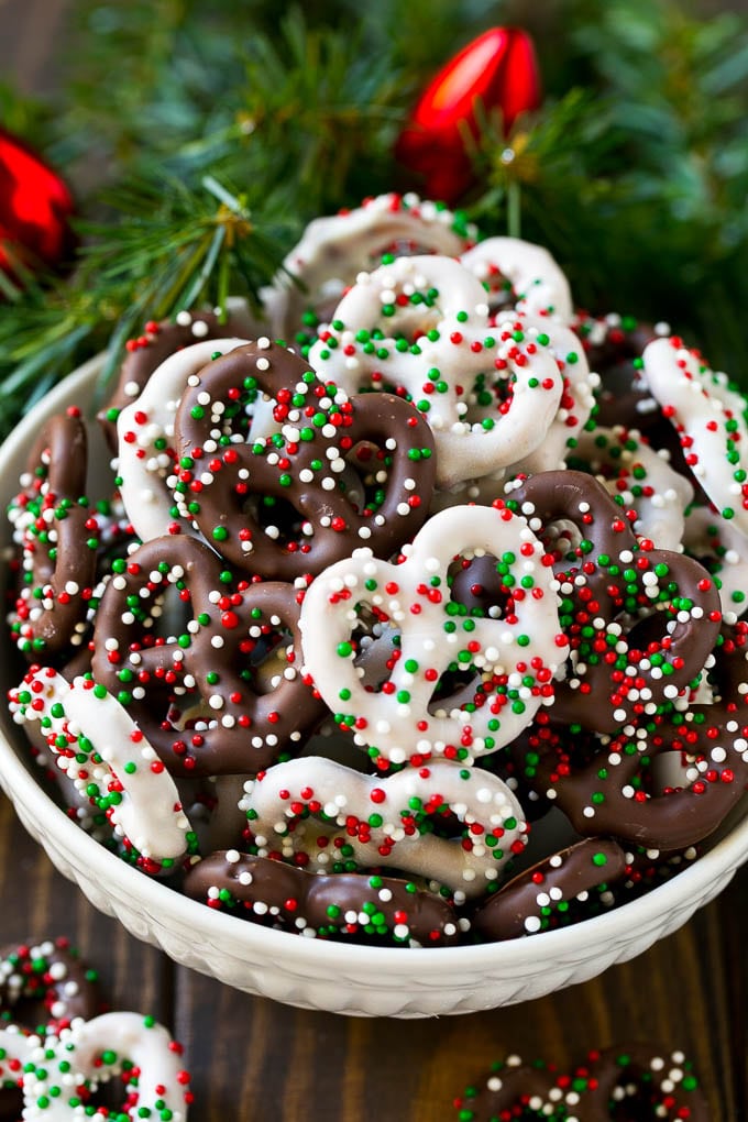 Chocolate Covered Pretzels Recipe | Sprinkle Pretzels | No Bake Dessert #pretzels #chocolate #christmas #sprinkles #candy #jonep Chocolate covered pretzels in a bowl with Christmas sprinkles.