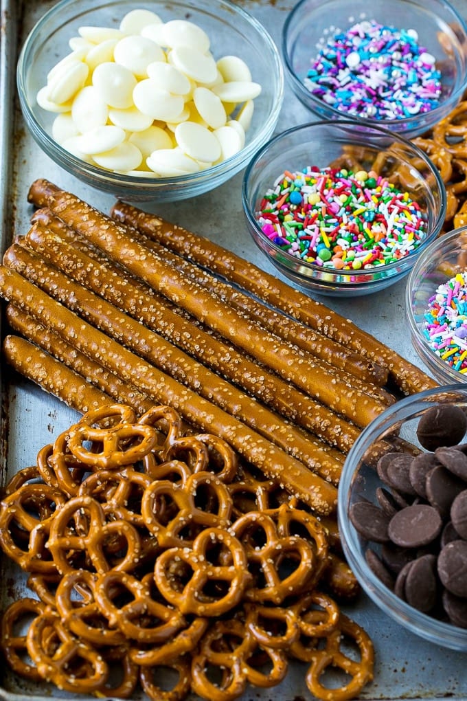 Chocolate Covered Pretzels Recipe | Sprinkle Pretzels | No Bake Dessert #pretzels #chocolate #christmas #sprinkles #candy #jonep Ingredients including candy melts and sprinkles on a sheet pan.
