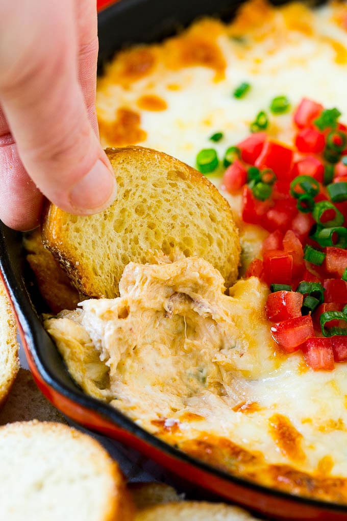 Crab Dip Recipe | Hot Crab Dip | Seafood Dip #dip #crab #seafood #appetizer #jonep #cheese A hand scooping out some crap dip with a crostini toast.