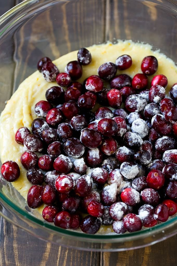 Cranberry Bread Recipe | Cranberry Loaf | Cranberry Orange Bread #cranberry #bread #baking #dessert #fall #jonep Orange batter topped with a pile of fresh cranberries in a mixing bowl.