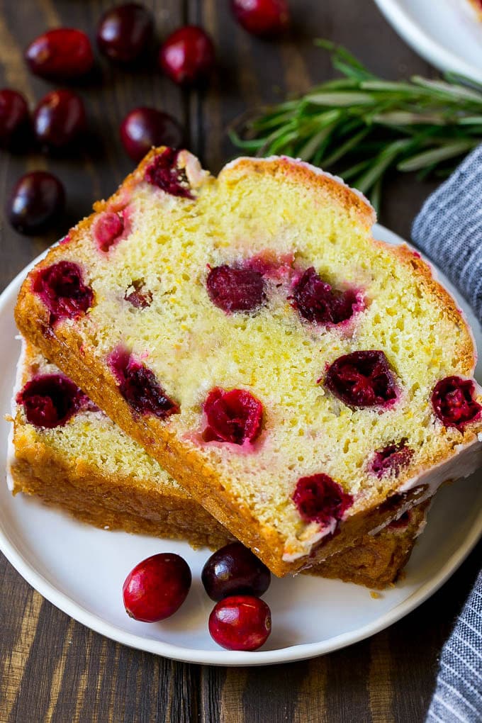 Cranberry Bread Recipe | Cranberry Loaf | Cranberry Orange Bread #cranberry #bread #baking #dessert #fall #jonep A plate with two slices of cranberry bread and fresh cranberries for garnish.