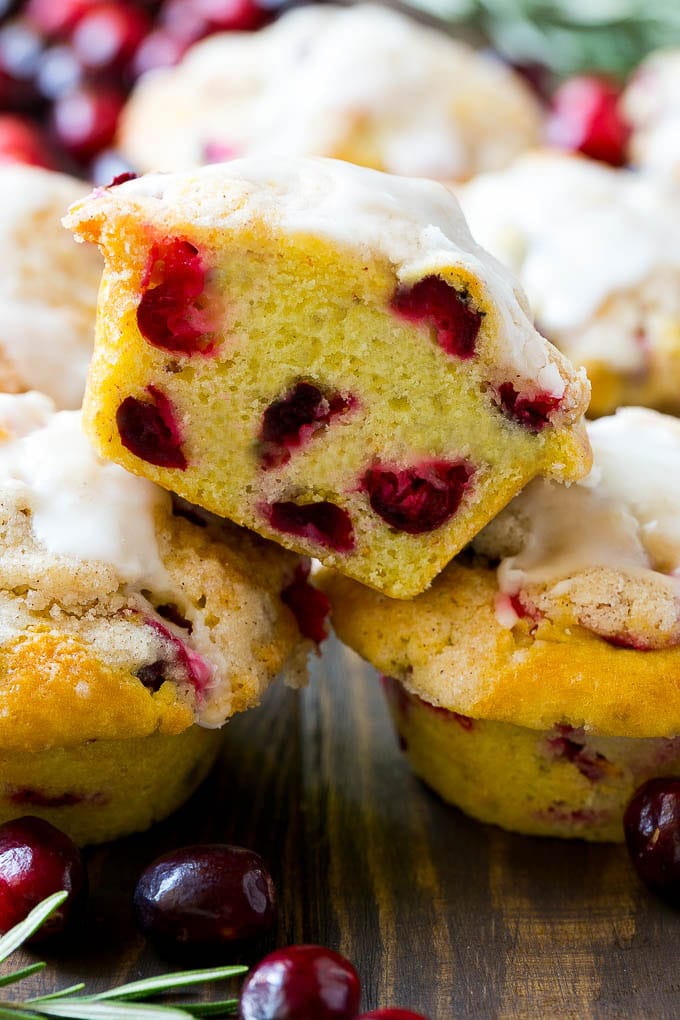 Cranberry Muffins Recipe | Cranberry Orange Muffins #cranberry #muffins #orange #fall #dessert #jonep A stack of cranberry muffins with one muffin cut in half.
