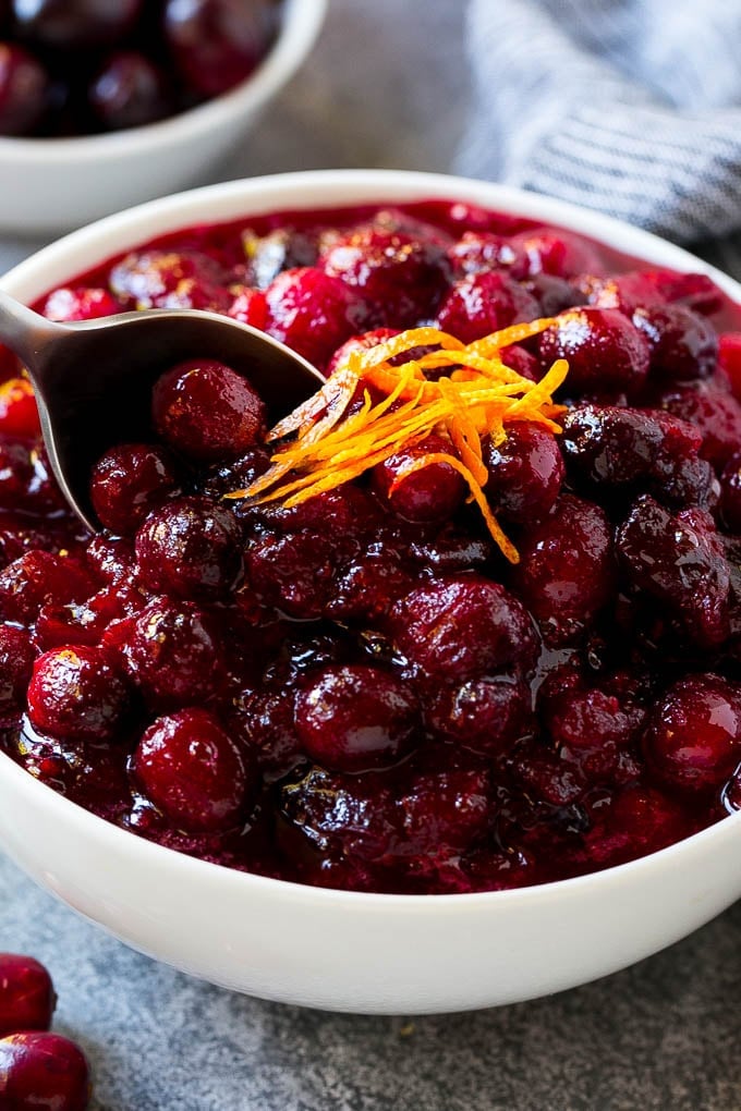 Cranberry Orange Sauce Recipe | Homemade Cranberry Sauce | Fresh Cranberry Sauce #cranberry #orange #fall #thanksgiving #sauce #dinner #jonep A serving spoon in a bowl of cranberry orange sauce.