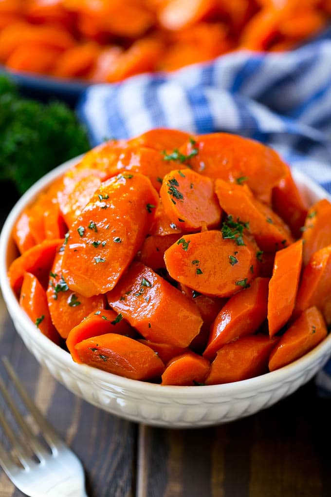 Glazed Carrots Recipe | Brown Sugar Carrots | Carrot Side Dish #carrots #brownsugar #sidedish #glutenfree #thanksgiving #fall #dinner #jonep A bowl of glazed carrots topped with parsley.