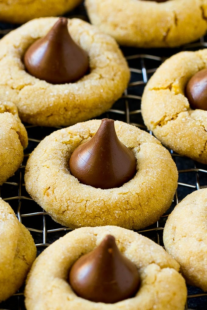 Peanut Butter Blossoms Recipe | Hershey Kiss Cookies | Chocolate Peanut Butter Cookies #cookies #peanutbutter #chocolate #dessert #baking #christmas #christmascookies #jonep Peanut butter blossom cookies on a cooling rack.