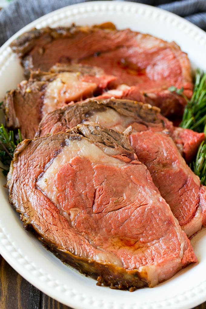 Smoked Prime Rib Recipe | Easy Prime Rib | Smoked Beef | Holiday Prime Rib #primerib #beef #smoker #dinner #jonep #christmas #thanksgiving #lowcarb #keto Slices of beef garnished with fresh herbs.