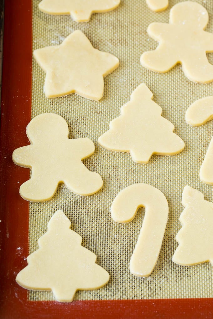 Christmas Sugar Cookies Recipe | Christmas Cookies #cookies #frosting #sprinkles #sugarcookies #christmas #dessert #jonep Cookie dough cut into holiday shapes on a baking sheet.