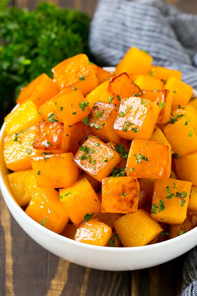 Roasted Butternut Squash Recipe | Baked Butternut Squash | Butternut Squash Side Dish #butternutsquash #squash #fall #vegetarian #dinner #jonep A bowl of roasted butternut squash made with brown sugar and maple syrup, then garnished with chopped parsley.