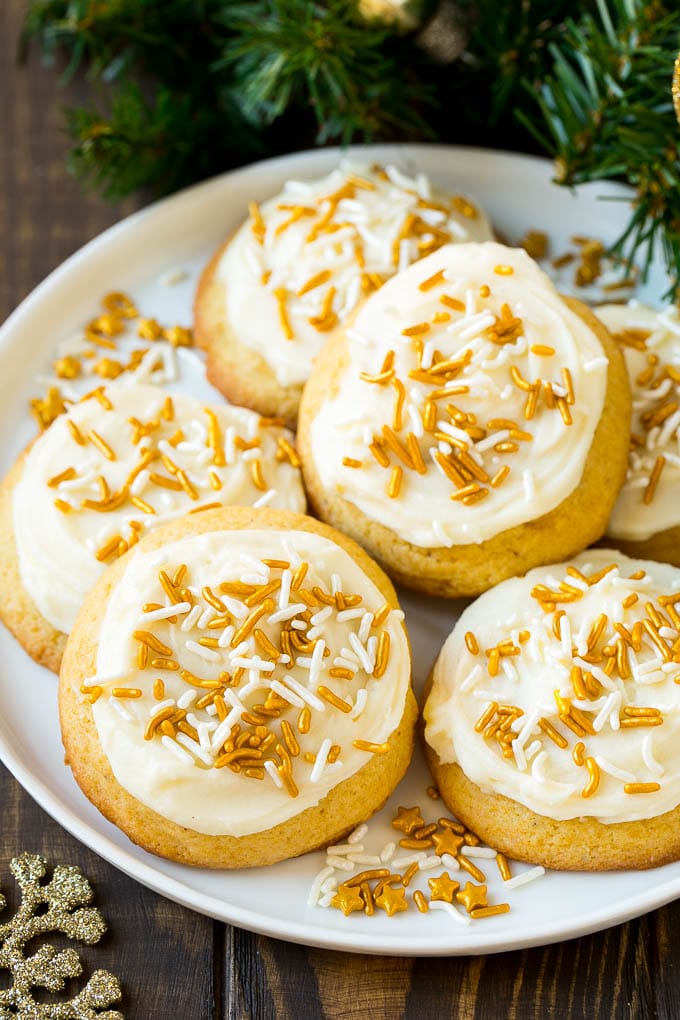 Eggnog Cookies Recipe | Holiday Cookies | Christmas Cookies #cookies #eggnog #baking #christmas #sprinkles #dessert #jonep Eggnog cookies topped with frosting and gold sprinkles on a serving plate.