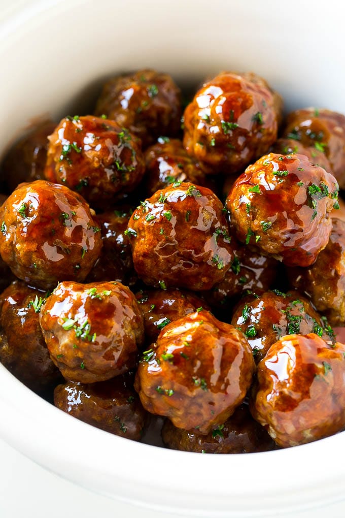 Sweet and Sour Meatballs Recipe | Slow Cooker Meatballs | Crockpot Meatballs | Cocktail Meatballs #meatballs #beef #slowcooker #crockpot #dinner #appetizer #jonep Sweet and sour meatballs garnished with parsley in a slow cooker.