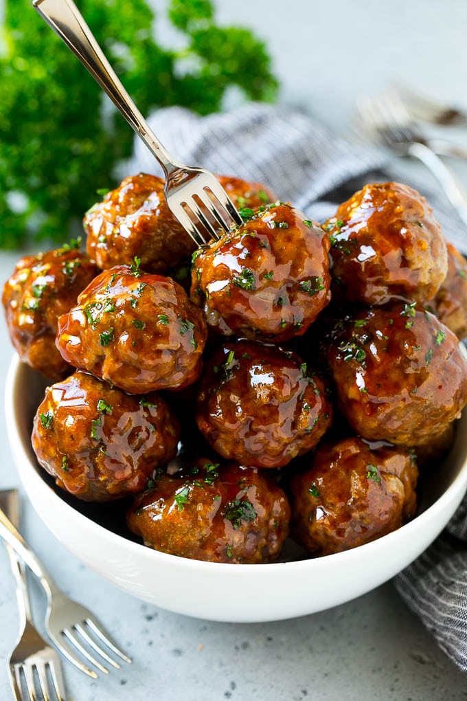 Sweet and Sour Meatballs Recipe | Slow Cooker Meatballs | Crockpot Meatballs | Cocktail Meatballs #meatballs #beef #slowcooker #crockpot #dinner #appetizer #jonep A bowl of sweet and sour meatballs with a cocktail fork in it.