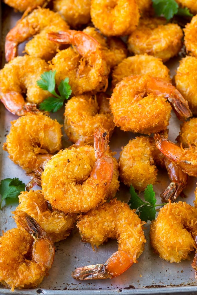 Coconut Shrimp Recipe | Fried Shrimp | Shrimp Appetizer #shrimp #coconut #appetizer #seafood #dinner #jonep A pile of crispy coconut shrimp on a sheet pan with cilantro leaves for garnish.