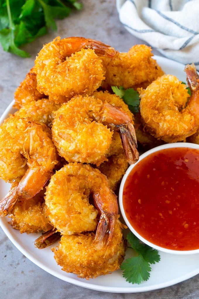 Coconut Shrimp Recipe | Fried Shrimp | Shrimp Appetizer #shrimp #coconut #appetizer #seafood #dinner #jonep A plate of coconut shrimp with a bowl of sweet chili sauce.