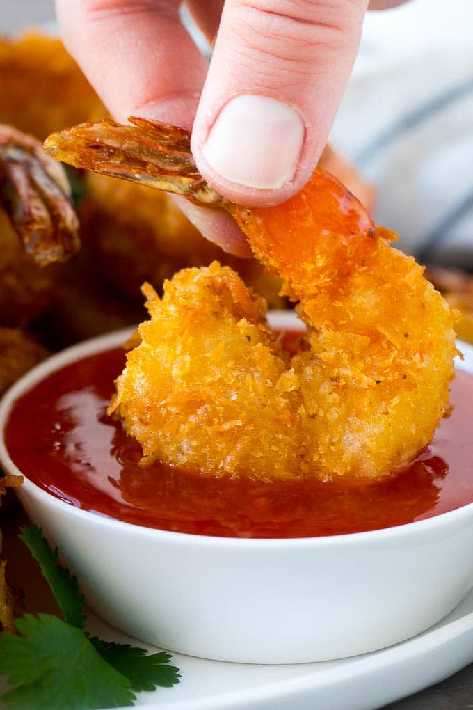 Coconut Shrimp Recipe | Fried Shrimp | Shrimp Appetizer #shrimp #coconut #appetizer #seafood #dinner #jonep A hand dipping a crispy prawn into a bowl of sweet chili sauce.