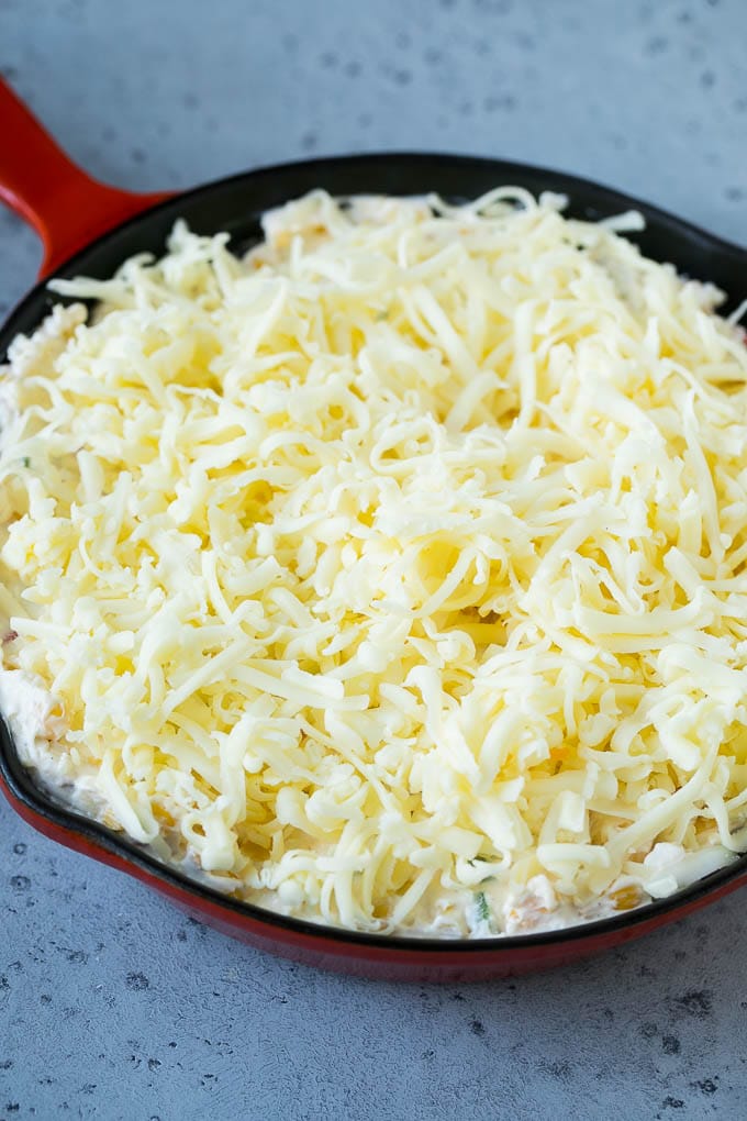Corn Dip Recipe | Hot Cheese Dip | Bacon Dip #corn #dip #bacon #cheese #appetizer #snack #jonep A skillet of corn dip covered with shredded cheese.