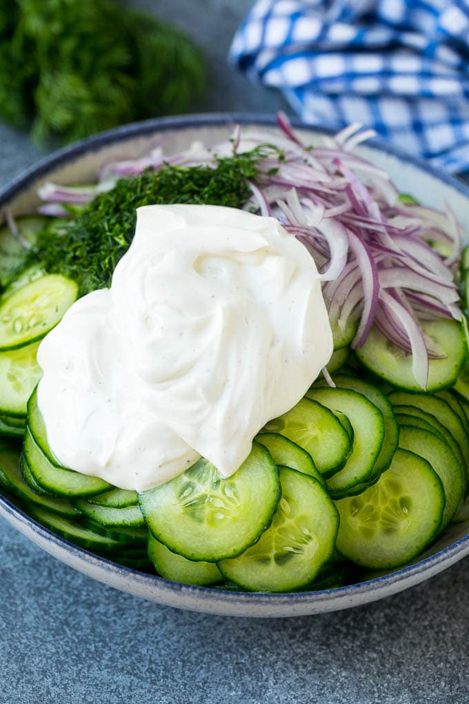 Creamy Cucumber Salad Recipe | German Cucumber Salad | Cucumber Salad #cucumber #salad #dinner #lunch #jonep #cucumbersalad Cucumbers, red onion and dill in a bowl topped with creamy dressing.