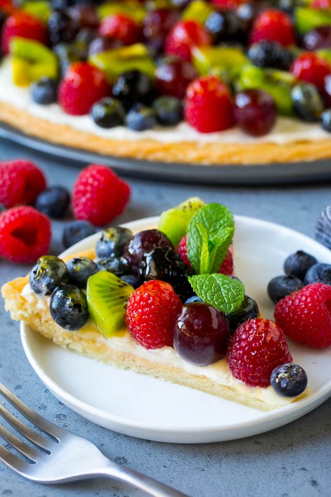 Fruit Pizza Recipe | Dessert Pizza | Fruit Dessert #cookie #fruit #pizza #dessert #sweets #jonep A slice of fruit pizza topped with cream cheese frosting and berries.