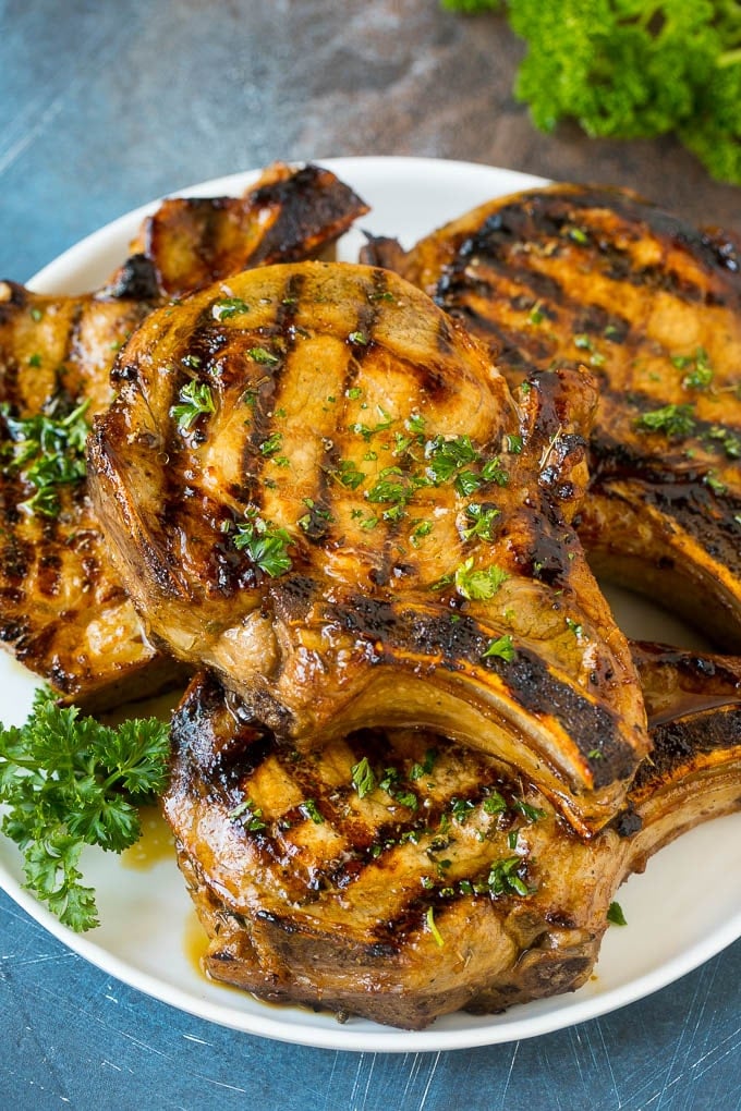 Pork Chop Marinade Recipe | Marinated Pork Chops | Grilled Pork Chops #pork #porkchops #grilling #dinner #jonep Pork chop marinade on grilled pork chops. The pork chops are on a serving plate garnished with parsley.