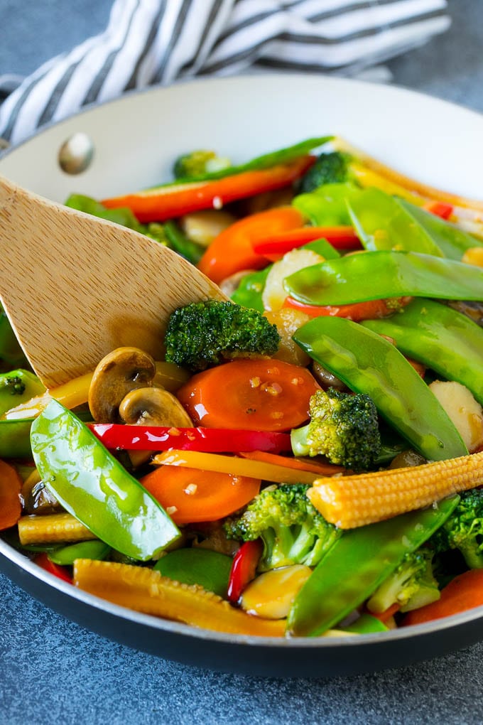 Vegetable Stir Fry Recipe | Veggie Stir Fry | Broccoli Stir Fry #vegetarian #vegetables #broccoli #dinner #jonep A spatula in a pan of veggie stir fry with carrots, snow peas and broccoli.