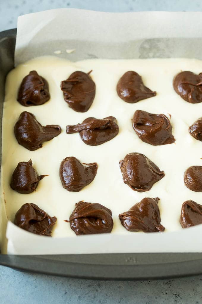 Cheesecake Brownies Recipe | Cream Cheese Brownies | Homemade Brownies #brownies #cheesecake #chocolate #dessert #jonep Brownies topped with a layer of cheesecake and dollops of chocolate batter.