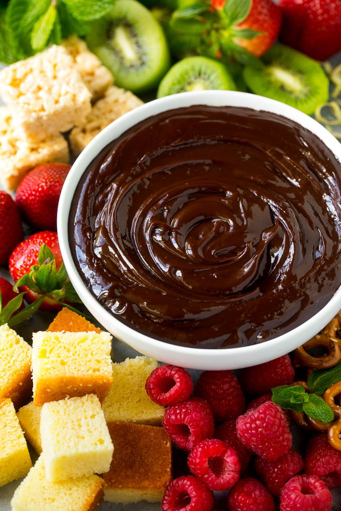 Chocolate Fondue Recipe | Chocolate Sauce | Chocolate Dip #chocolate #dessert #glutenfree #fondue #jonep A bowl of chocolate fondue surrounded by fruit, cake, rice krispy treats and pretzels.