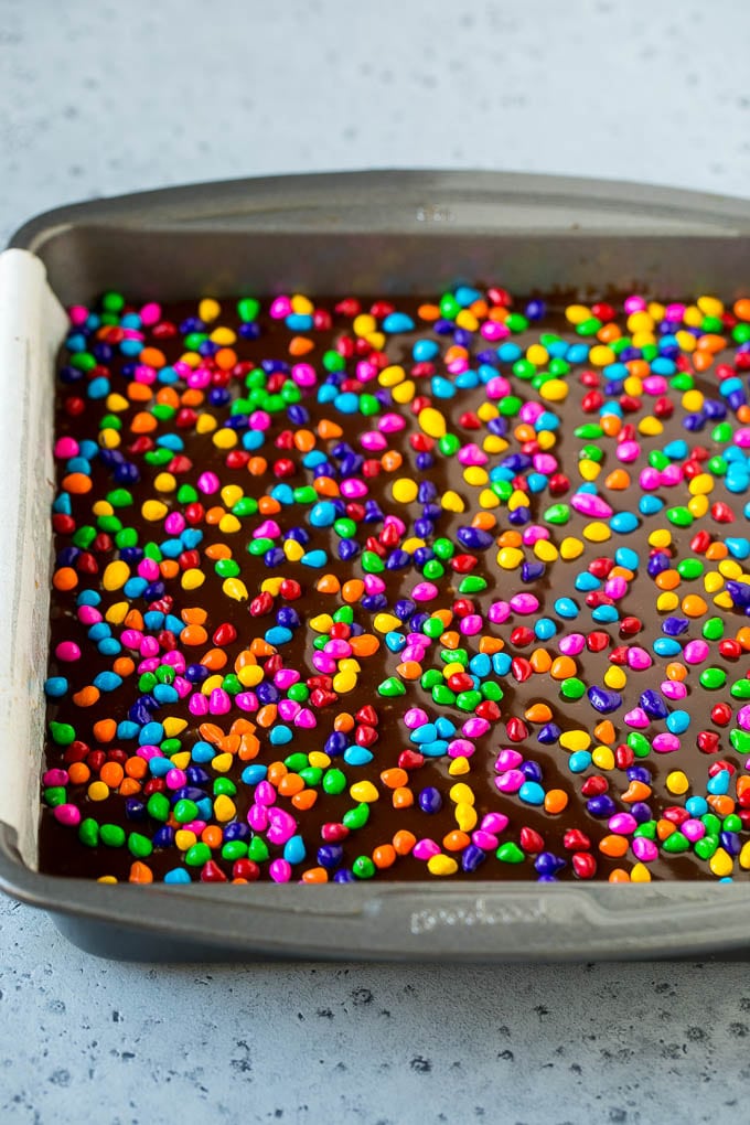 Cosmic Brownies Recipe | Cocoa Brownies | Frosted Brownies #brownies #chocolate #dessert #jonep #sprinkles A pan of cosmic brownies with rainbow sprinkles on top.