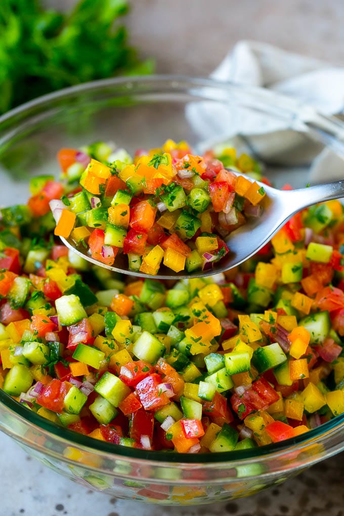 Israeli Salad Recipe | Cucumber Salad | Tomato Salad | Chopped Salad #salad #cleaneating #healthy #glutenfree #lowcarb #keto #sidedish #lunch #jonep A spoon holding up a serving of Israeli salad.