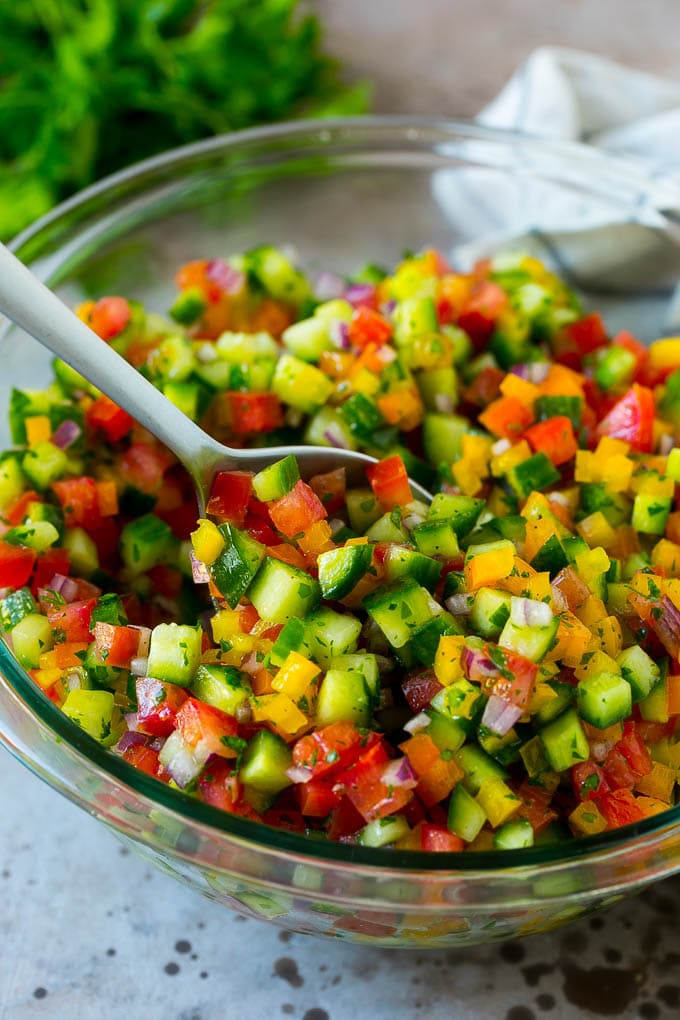 Israeli Salad Recipe | Cucumber Salad | Tomato Salad | Chopped Salad #salad #cleaneating #healthy #glutenfree #lowcarb #keto #sidedish #lunch #jonep A bowl of Israeli salad with a serving spoon in it.