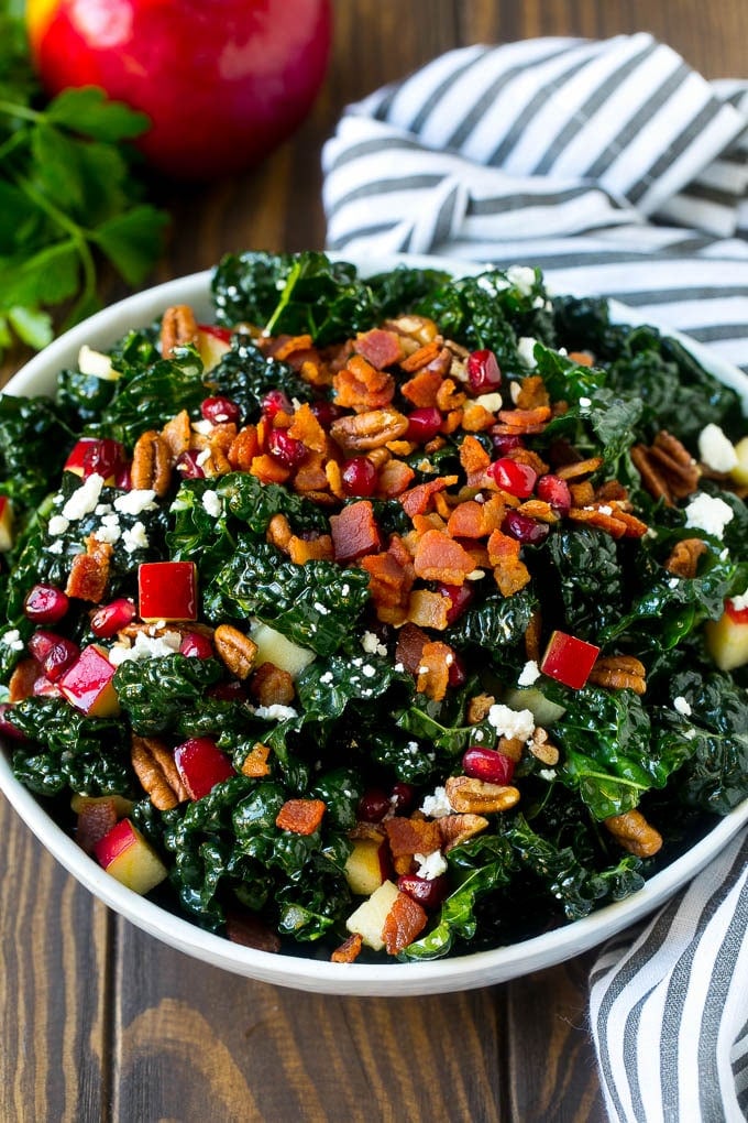 Apple Kale Salad Recipe | Kale Recipe | Fall Salad #kale #apples #bacon #salad #feta #dinner #lunch #jonep A bowl of tuscan kale salad garnished with cooked bacon.