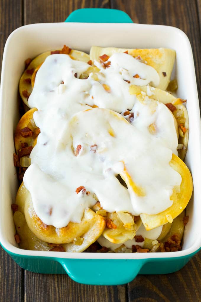 Pierogi Casserole Recipe | Potato Casserole #pierogis #casserole #bacon #cheddar #dinner #jonep Dumplings in a baking dish covered with creamy sauce.