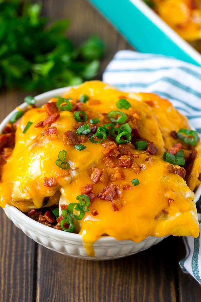 Pierogi Casserole Recipe | Potato Casserole #pierogis #casserole #bacon #cheddar #dinner #jonep A bowl of pierogi casserole topped with cheddar cheese and bacon.