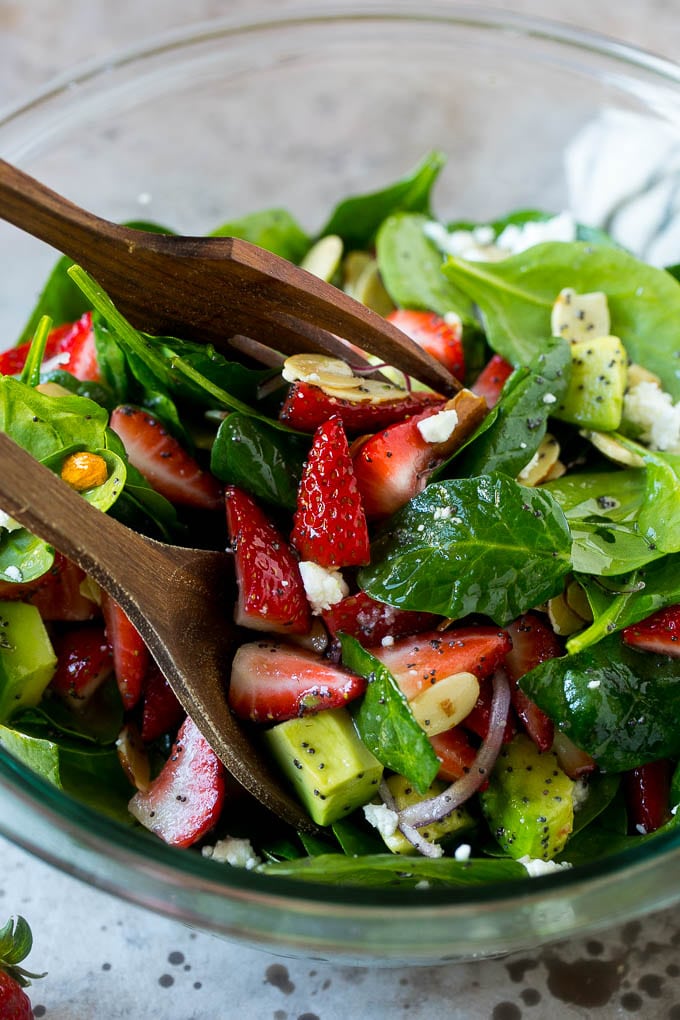 Strawberry Spinach Salad Recipe | Strawberry Salad | Spinach Salad #spinach #salad #strawberries #avocado #jonep Salad tongs in a bowl of spinach salad with strawberries.