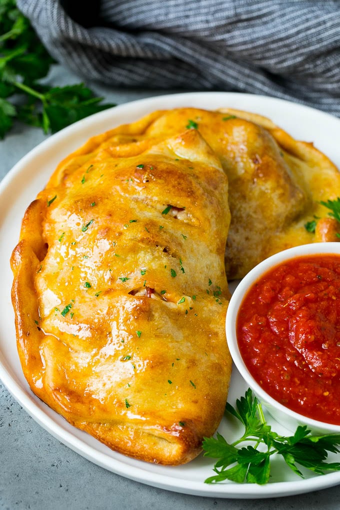 Calzone Recipe | Pizza Pockets #pizza #calzone #pepperoni #sausage #peppers #dinner #jonep #cheese A homemade calzone served with pizza sauce.