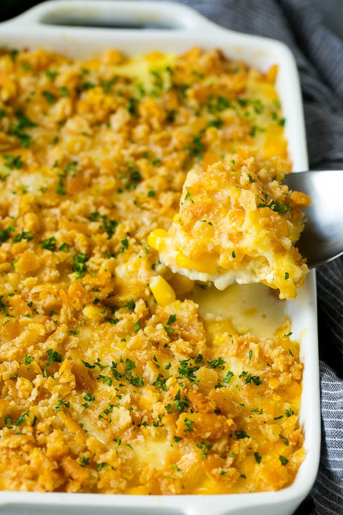 Scalloped Corn | Corn Casserole #corn #casserole #cheese #sidedish #dinner #jonep A serving spoon lifting out a portion of scalloped corn.
