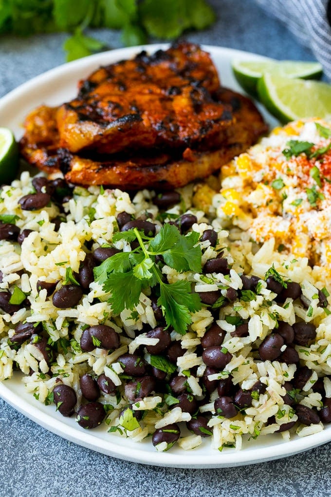 Black Beans and Rice Recipe | Cuban Black Beans | Beans and Rice #beans #rice #blackbeans #sidedish #glutenfree #dinner #jonep A plate of black beans and rice with grilled pork and Mexican corn.