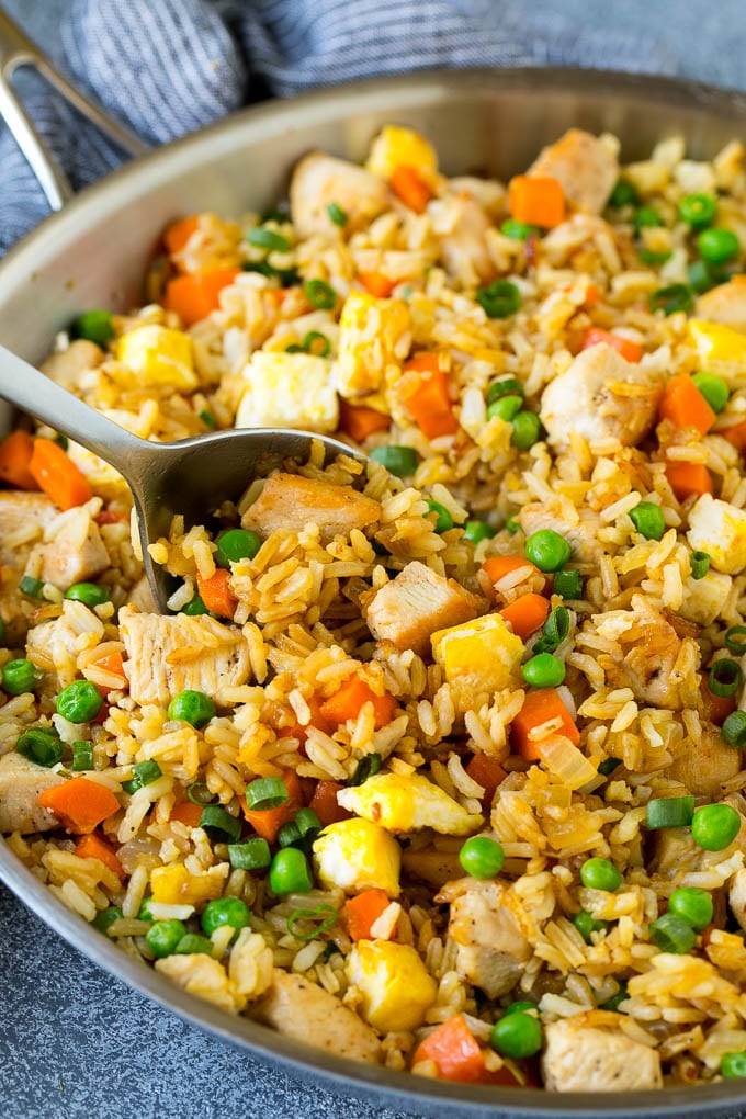 Chicken Fried Rice Recipe | Chinese Fried Rice #rice #chicken #peas #carrots #sidedish #dinner #jonep A serving spoon in a pan of chicken fried rice.