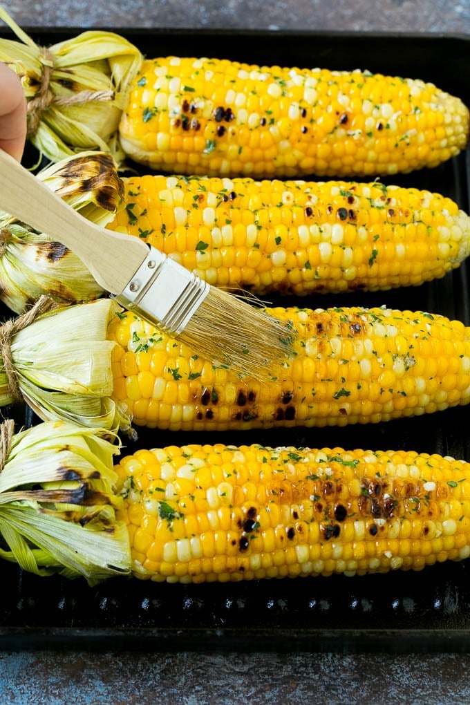 Grilled Corn on the Cob Recipe | Corn Recipe #corn #grilling #summer #sidedish #dinner #jonep Cobs being brushed with herb butter.