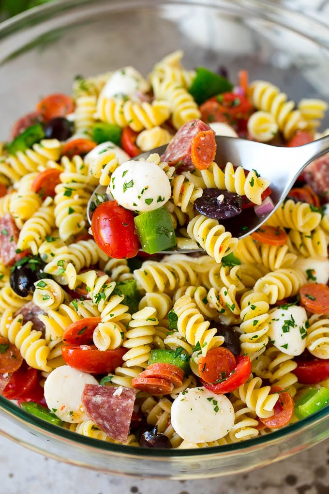 Italian Pasta Salad | Pasta Salad Recipe #pasta #salad #pastasalad #pepperoni #salami #olives #cheese #sidedish #jonep A serving spoon in a bowl of Italian style pasta salad.