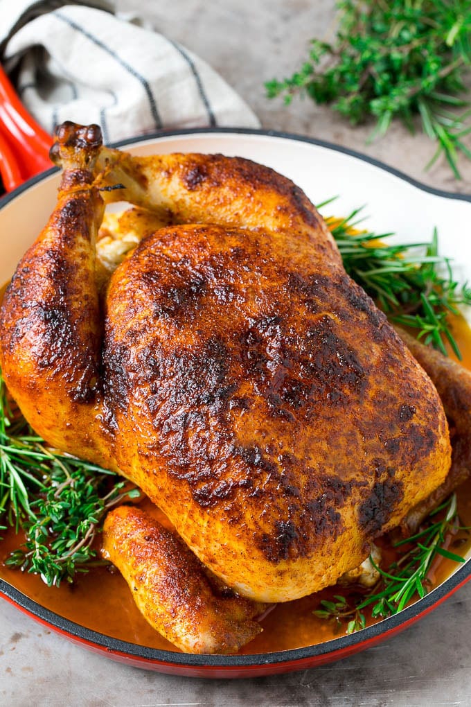Rotisserie Chicken Recipe | Roasted Chicken #chicken #dinner #jonep #comfortfood A rotisserie chicken in a red skillet with sprigs of fresh herbs.