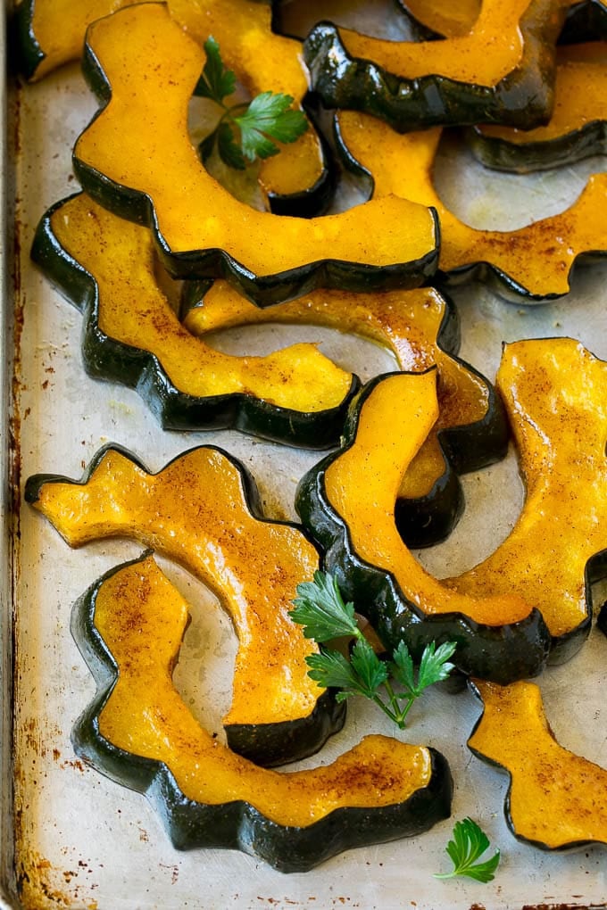 Roasted Acorn Squash | Acorn Squash Recipe #squash #winter #sidedish #dinner #jonep Sliced of cinnamon roasted acorn squash on a sheet pan.